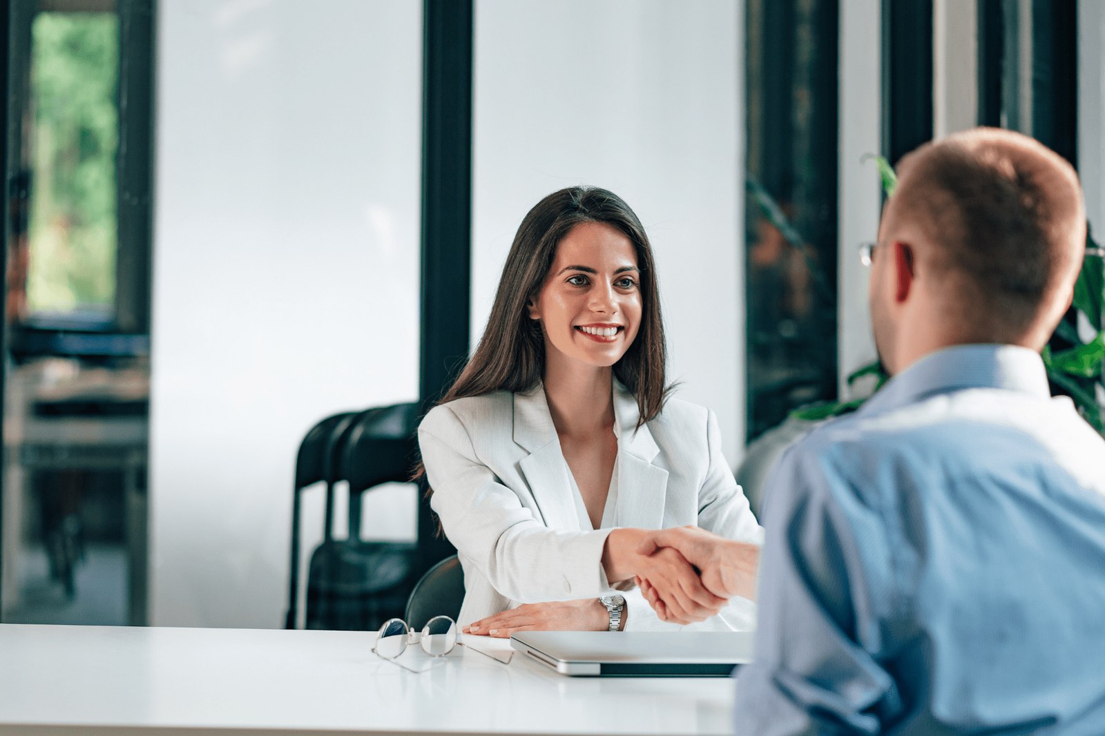 A recruiter shaking hands with a driver candidate across the interview desk